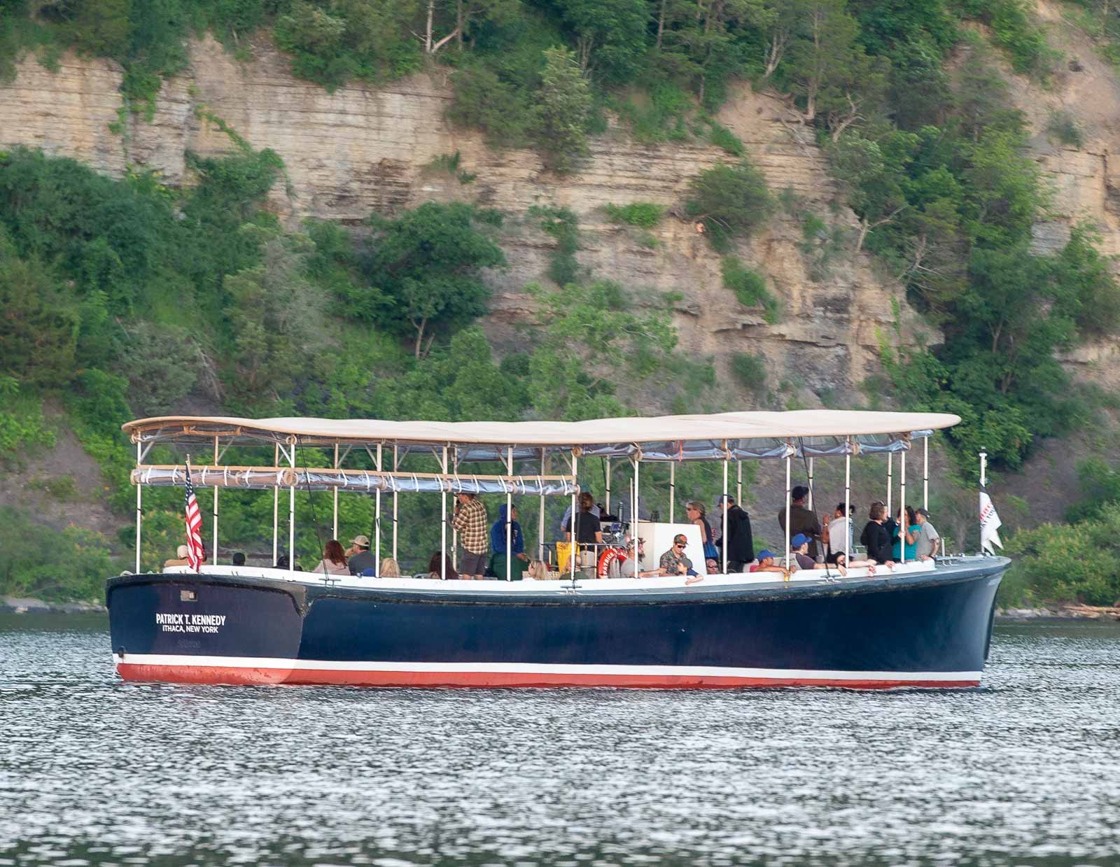 Passengers enjoying a narrated sunset cruise aboard the M/V Patrick T. Kennedy on Cayuga Lake near Ithaca, New York during golden hour.